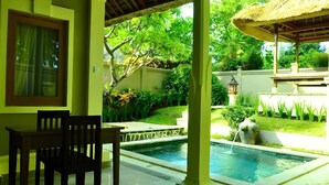 A covered outdoor area with a pool, a table with chairs, and a thatched roof structure. - New Sunari Lovina Beach Resort (Buleleng)