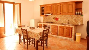 A kitchen with wooden cabinets, a tiled backsplash, and a dining area with a table and chairs.