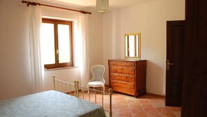 A bedroom with a bed, a dresser, a chair, and a window with curtains.