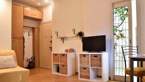Een gezellige woonkamer met een bank, een televisie, rieten manden en een glazen salontafel.