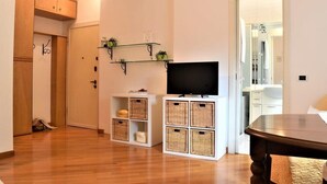 Een moderne woonkamer met een flatscreen televisie, rieten manden en een houten kast.