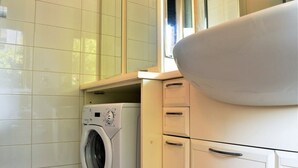 Een praktische keuken met een ingebouwde wasmachine, een spoelbak en een raam.