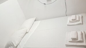 Un letto rifatto con lenzuola bianche e un asciugamano piegato sul lato destro.