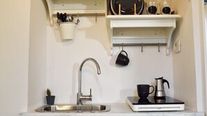 Una cucina con lavandino, una macchina per il caffè e utensili su uno scaffale.