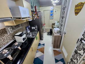 A compact kitchen with a microwave, coffee maker, and a refrigerator. - Elegant Studio @ Grass Residences 1-5 persons only, Quezon City (Quezon City)