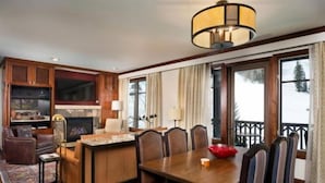 A cozy living room with a fireplace, wooden furniture, and a large window overlooking a snowy landscape. - Aspen Ritz-carlton 2 Bedroom Ski in, Ski out Residence With Access to Slopeside Heated Pools and Hot Tubs (Aspen)