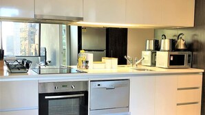Une cuisine moderne dotée d’appareils électroménagers intégrés, d’une grande fenêtre et offrant une vue sur la ville.