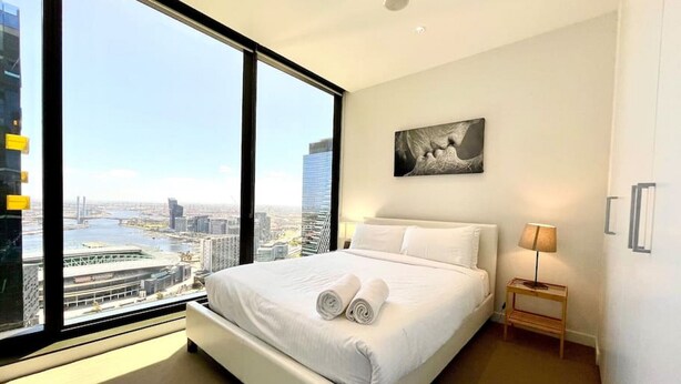 Une chambre à coucher moderne avec un grand lit, une vue sur la ville et un tableau accroché au mur.