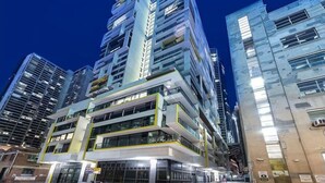 Un immeuble moderne de grande hauteur, doté de nombreux étages, de grandes fenêtres et d’un hall d’entrée imposant.