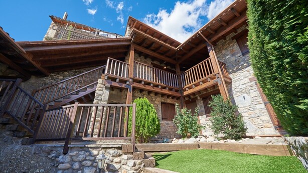 Un edificio rústico de piedra con balcones de madera y una escalera de piedra.