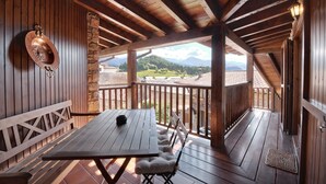 Una terraza de madera con una mesa y bancos, con vistas a un paisaje montañoso.