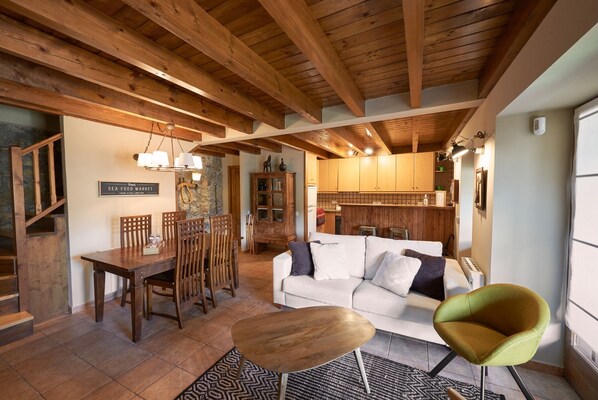 A cozy living room with a wooden dining table, a sofa, and a green armchair.