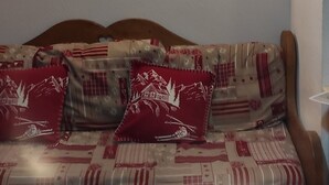 A living room with a sofa, pillows, a painting, and a table.