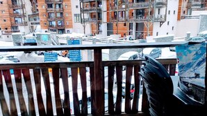 A wooden deck with a view of multi-story buildings, including balconies and a ski resort sign.