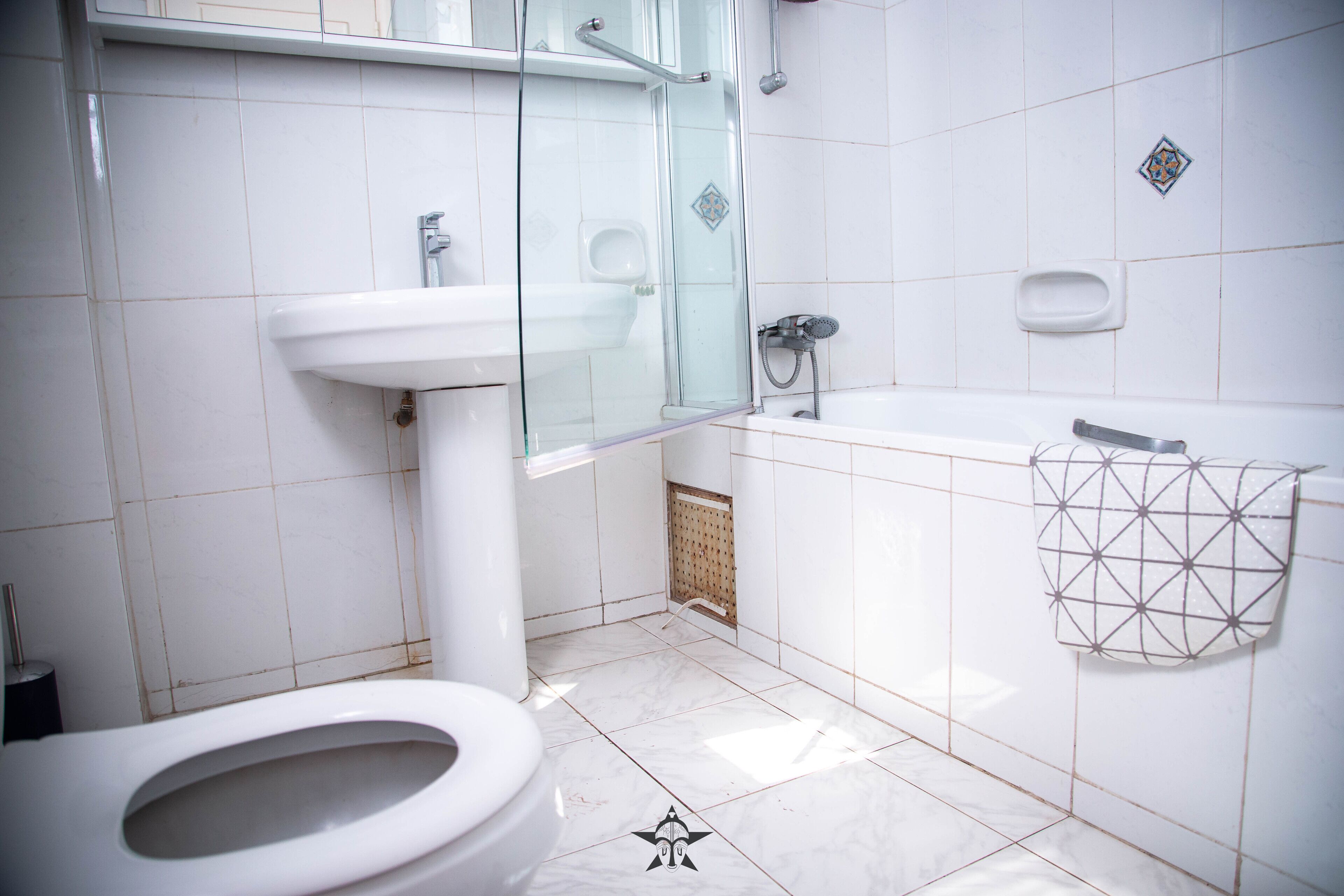 Et moderne badeværelse med en glasbrusekabine, en hvid vask og et toilet.