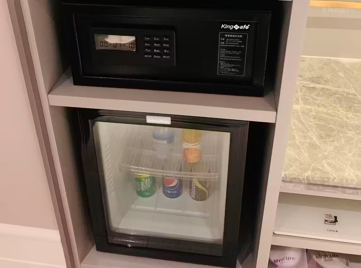 Uma geladeira compacta com visor digital, um pequeno compartimento de congelador e uma prateleira acima.