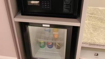 A compact refrigerator with a digital display, a small freezer compartment, and a shelf above it.