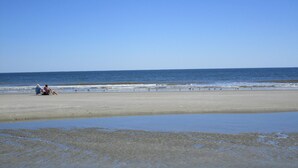 A beach with a clear sky, calm sea, and a few people sitting on the sand. - Labor Day Special! 2 bd/2 bath! 3 Pools-Walk to Beach (Hilton Head Island)