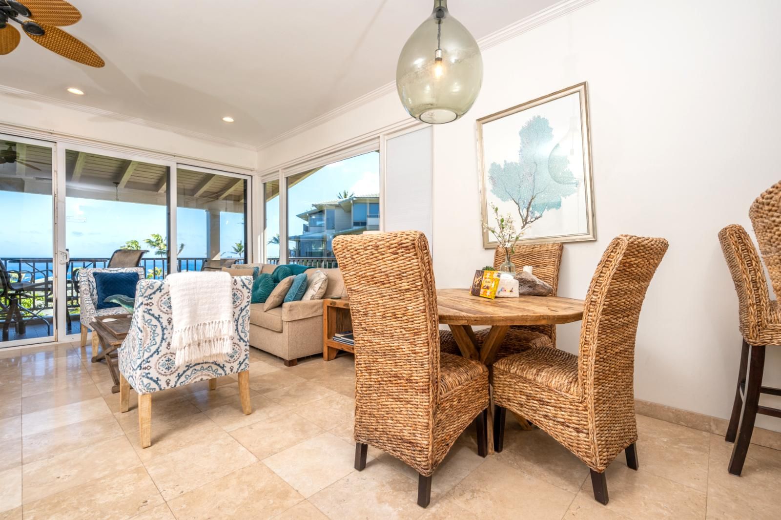 A dining area with wicker chairs, a wooden table, and a ceiling fan.