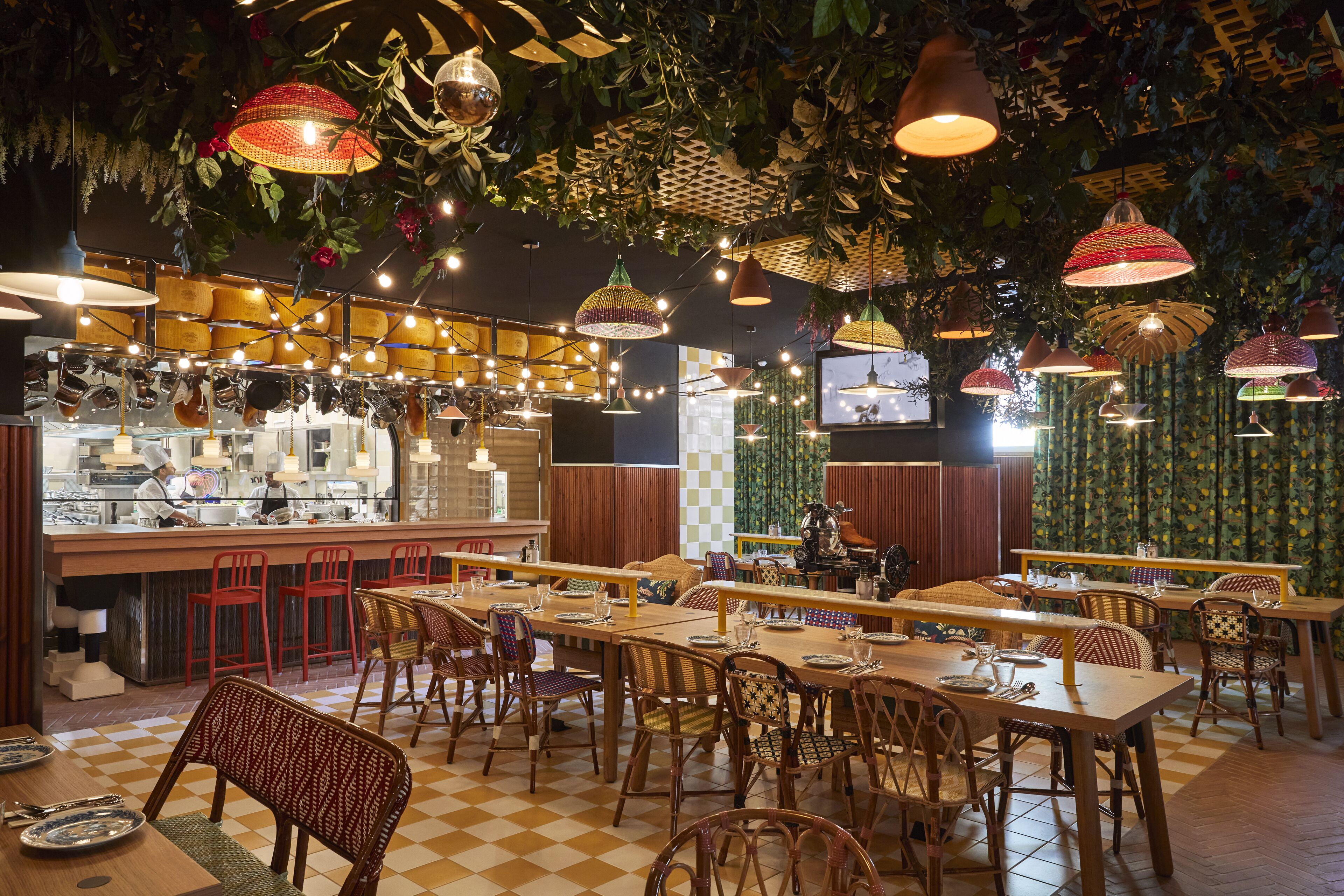 Un restaurante con mesas y sillas de madera, lámparas colgantes y una zona de bar.