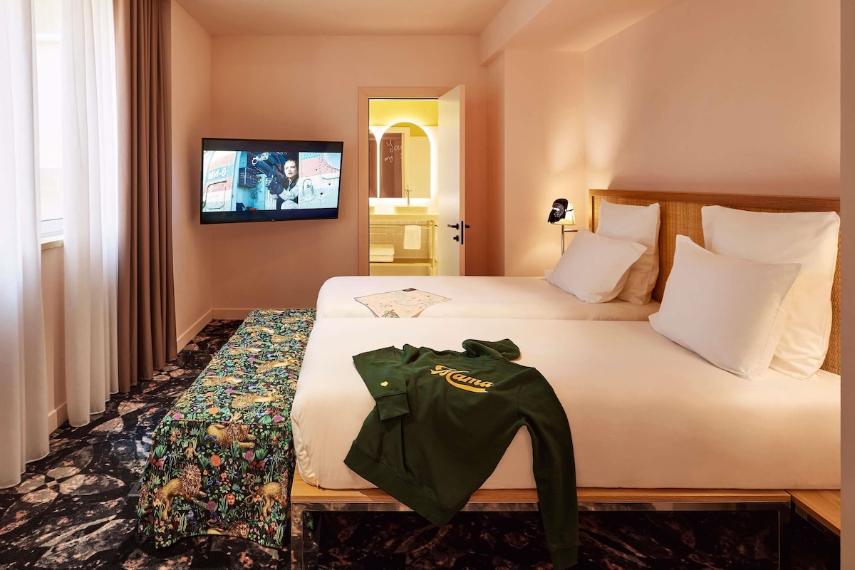 Ein Hotelzimmer mit Bett, Fernseher, Spiegel und einem Fenster mit Vorhängen.