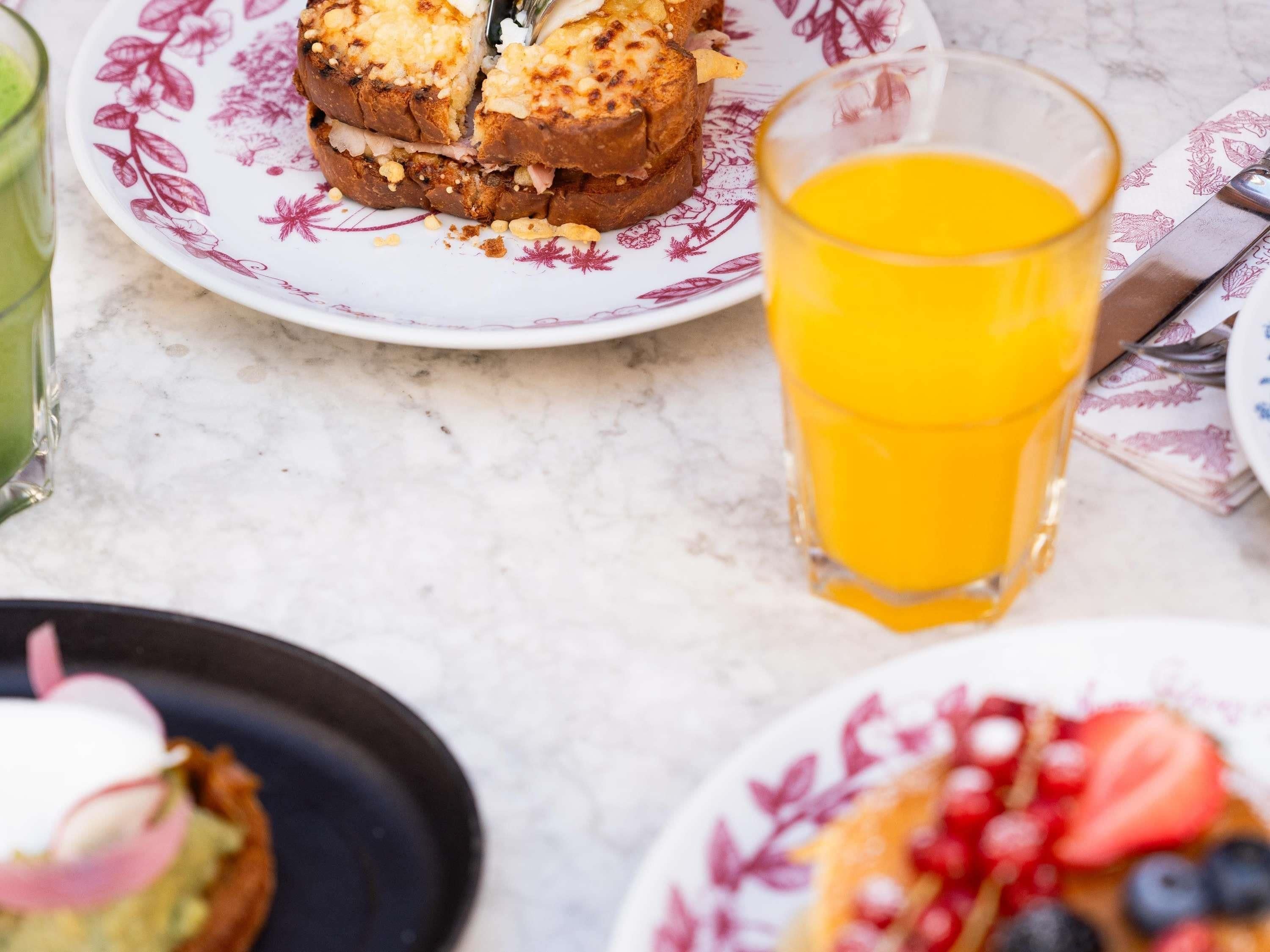 Una colazione con un piatto di cibo, un bicchiere di succo d'arancia e una tovaglietta.