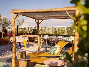 An outdoor seating area with wicker furniture, tables, and a canopy structure. - Mama Shelter Roma  (Rome)