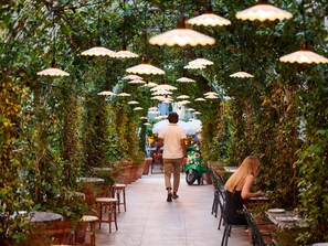 An indoor pathway lined with tables and chairs, covered by a canopy of hanging lamps. - Mama Shelter Roma  (Rome)