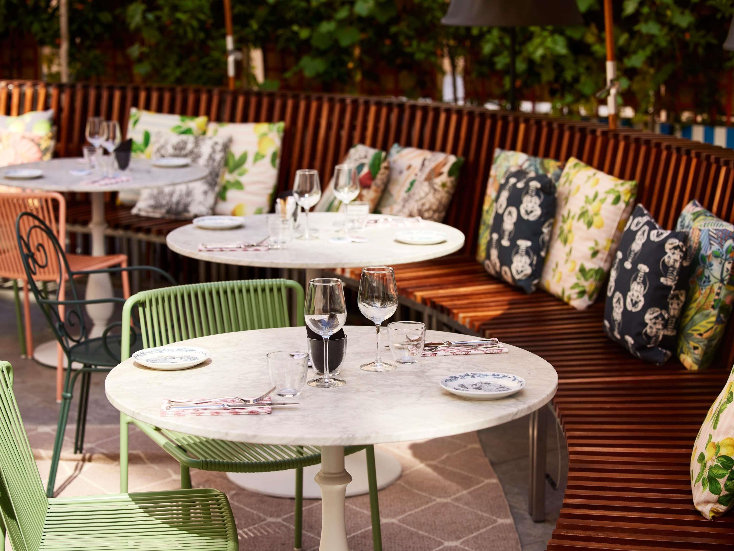 A restaurant with round tables, green chairs, and cushioned seating.