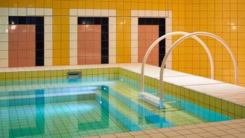 An indoor swimming pool with tiled walls and a tiled floor.