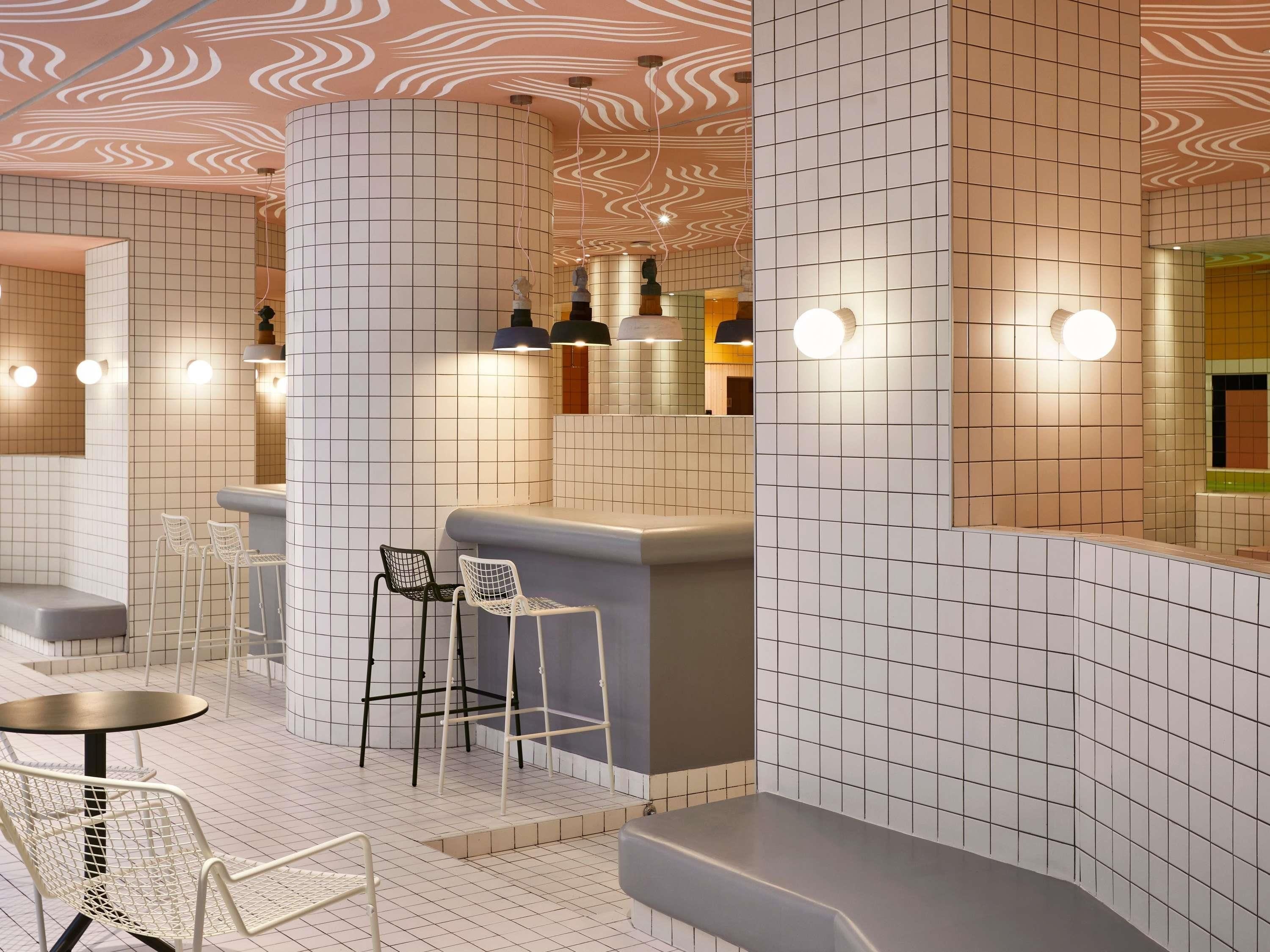 Un intérieur moderne avec un mur recouvert de carreaux, un coin bar et des sièges.