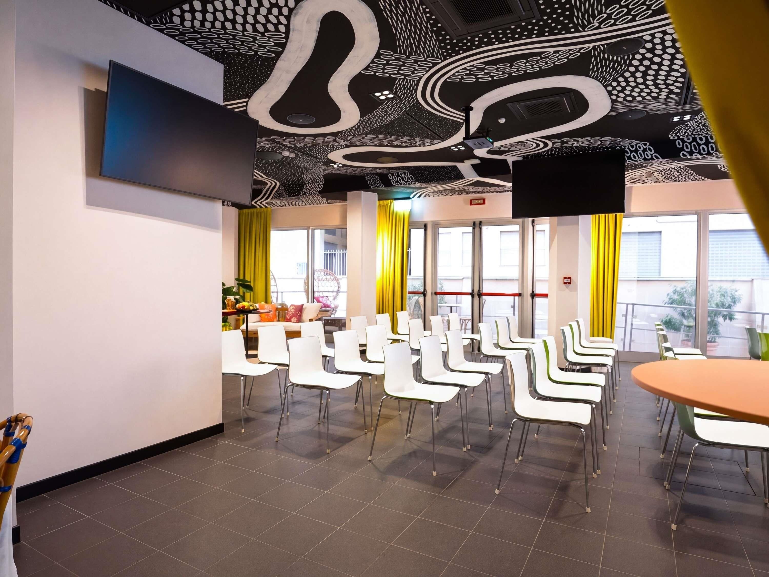 A conference room with white chairs, a round table, and a ceiling with a unique design.