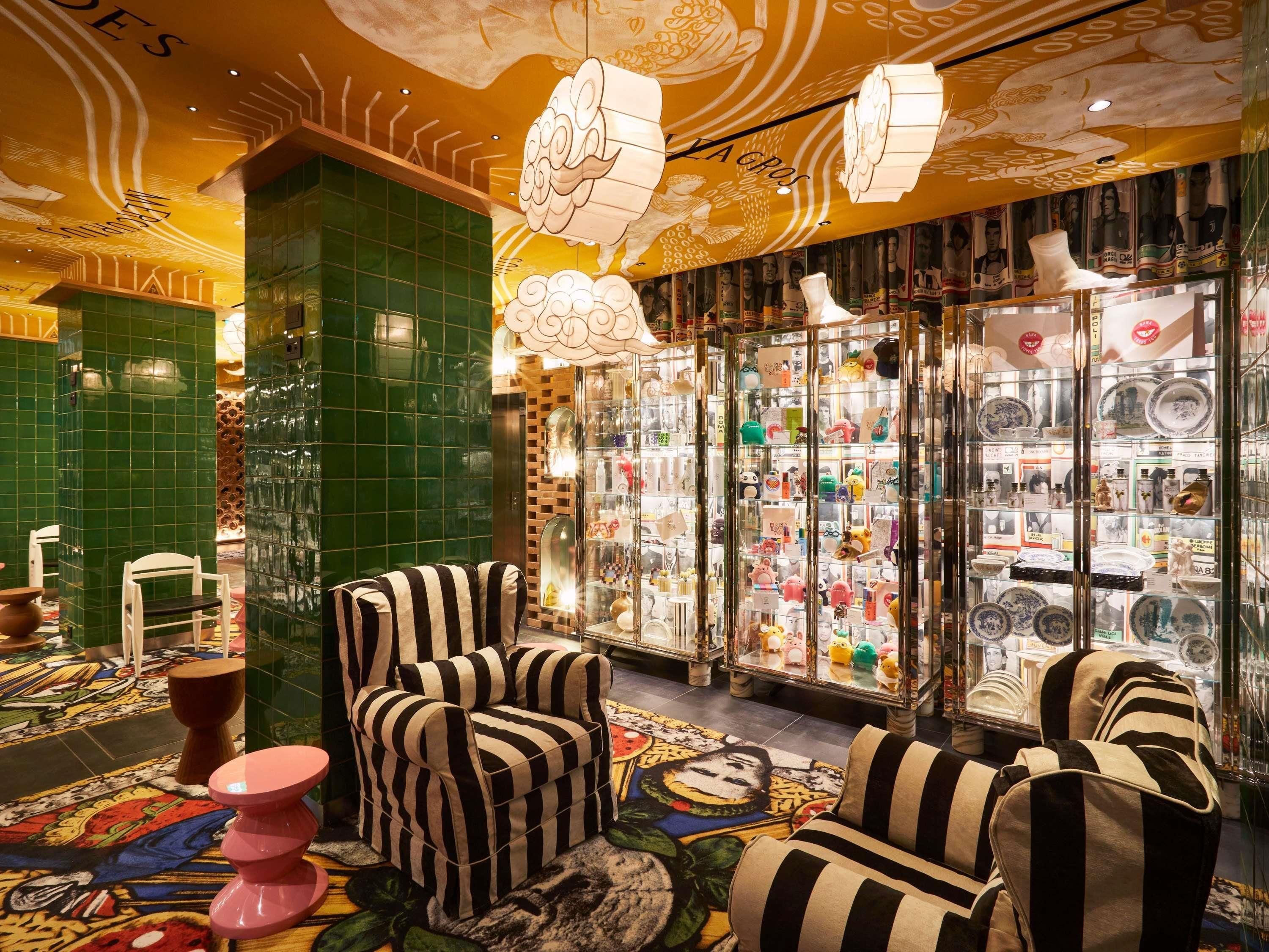 A room with striped chairs, a glass display case with various items, and a green-tiled wall.