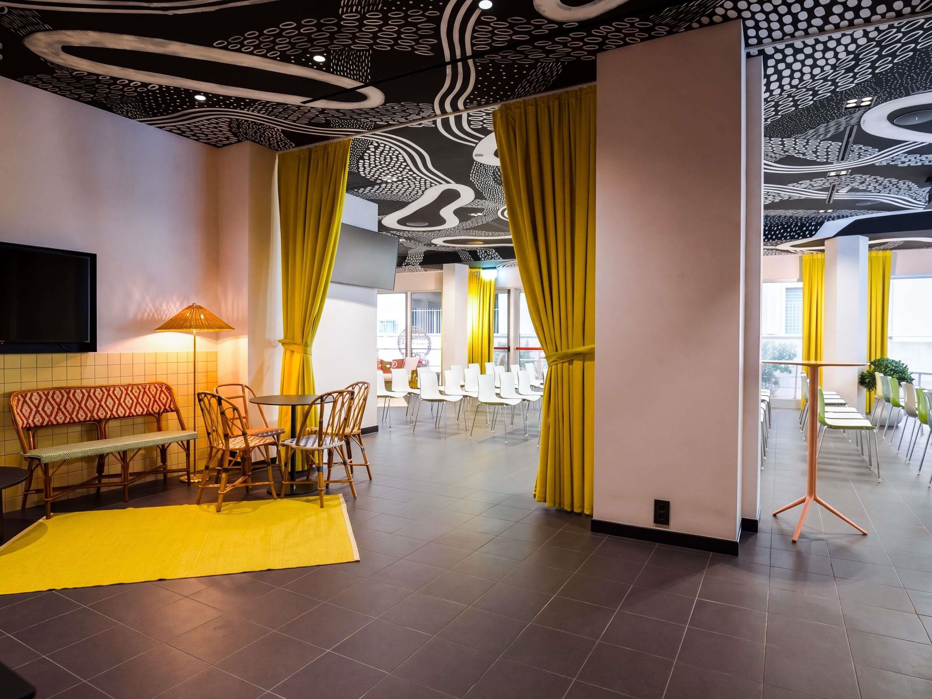 A modern interior with a seating area featuring a bench and chairs, a flat-screen TV mounted on the wall, and a patterned floor.