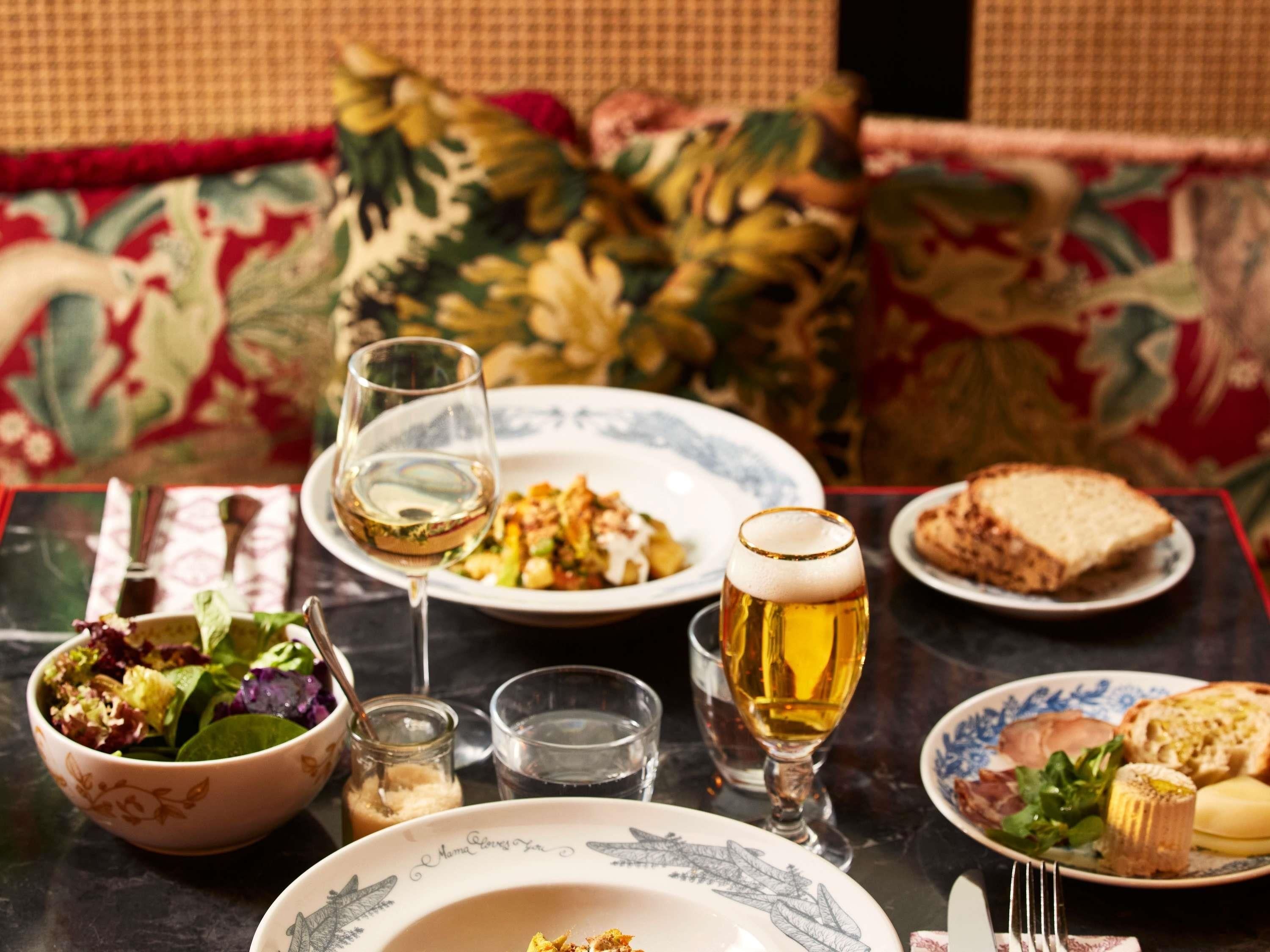 A dining table with plates of food, glasses of wine, and a bowl of salad.