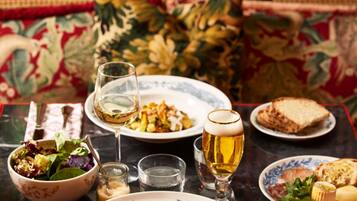 A dining table with plates of food, glasses of wine, and a bowl of salad.