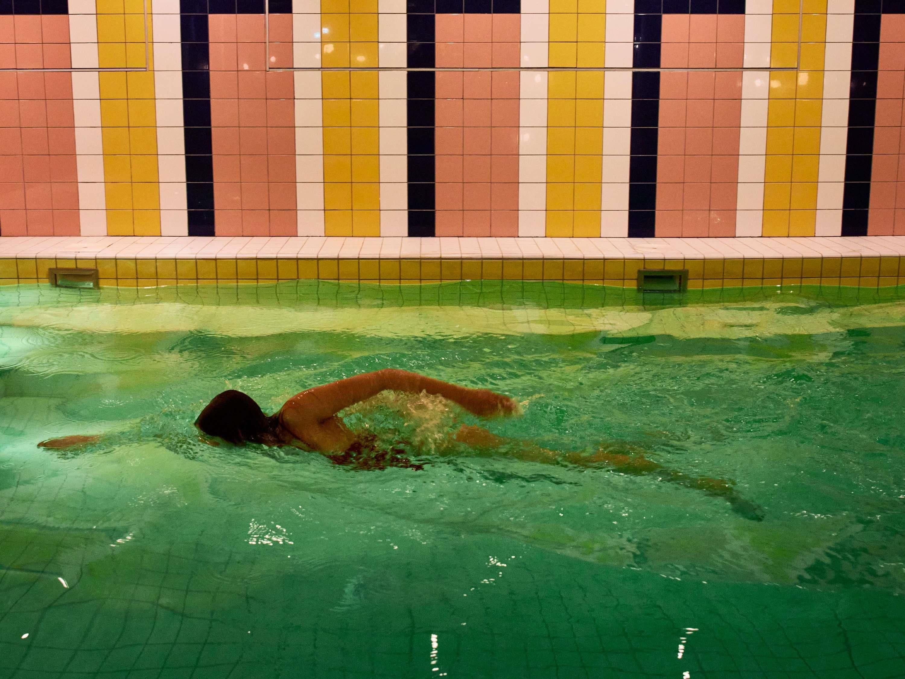 A swimming pool with a tiled wall featuring a pattern of vertical stripes in various colors.