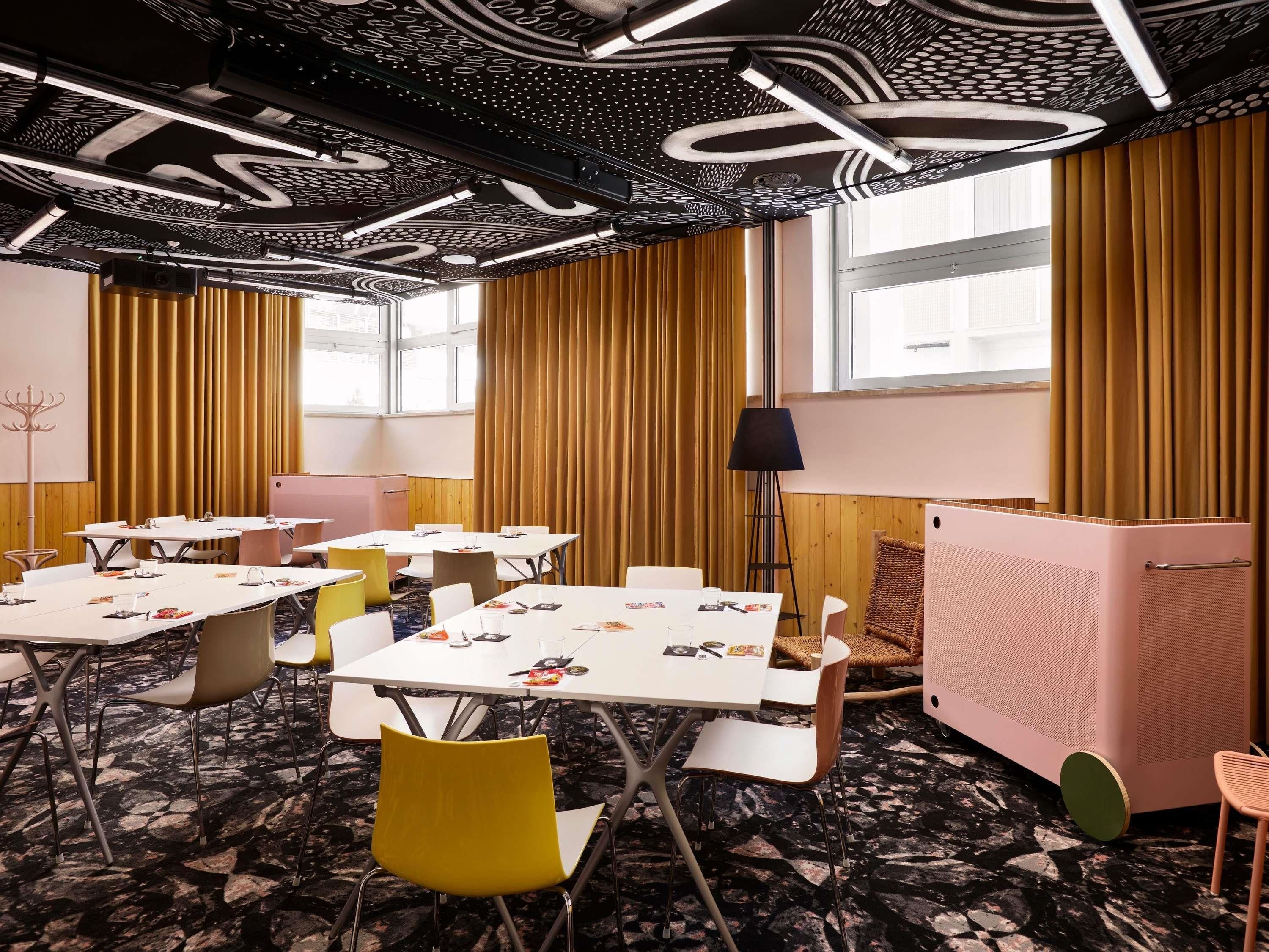 A conference room with tables, chairs, a standing lamp, and a refrigerator.
