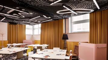 A conference room with tables, chairs, a standing lamp, and a refrigerator.