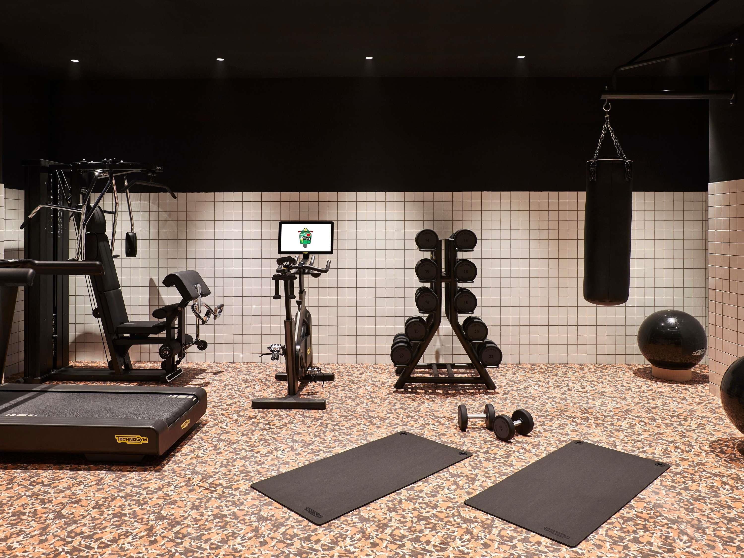 A gym with exercise equipment, a punching bag, and a digital screen.