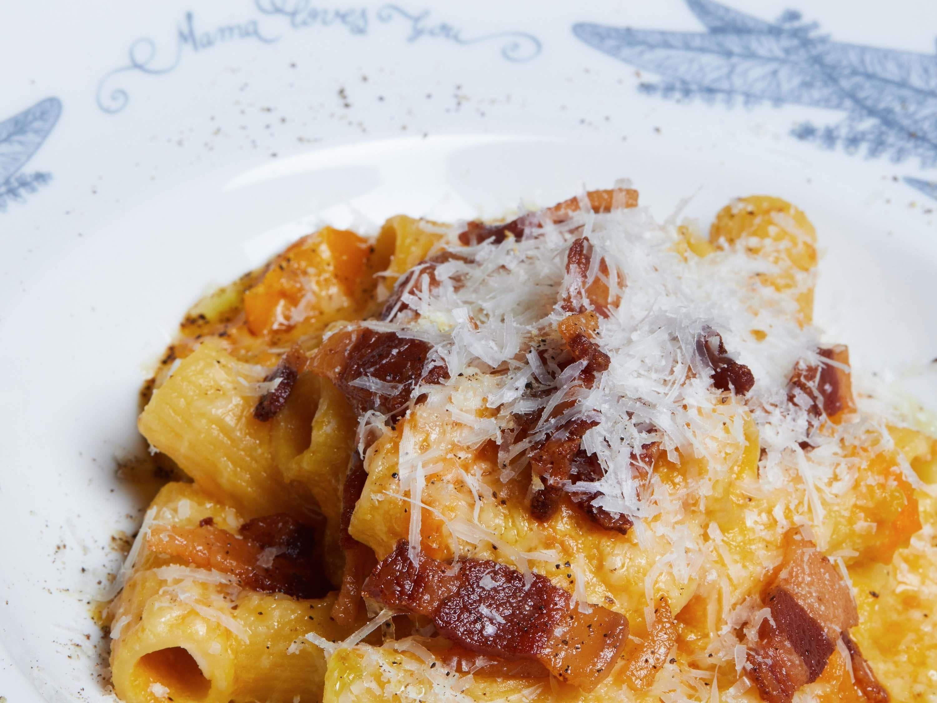 A plate of pasta with cheese and bacon.