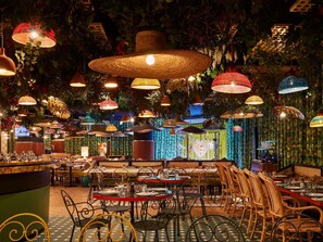 A restaurant with multiple tables, hanging lamps, and a decorative wall. - Mama Shelter Roma  (Rome)