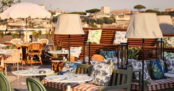 An outdoor dining area with round tables, chairs, and umbrellas.
