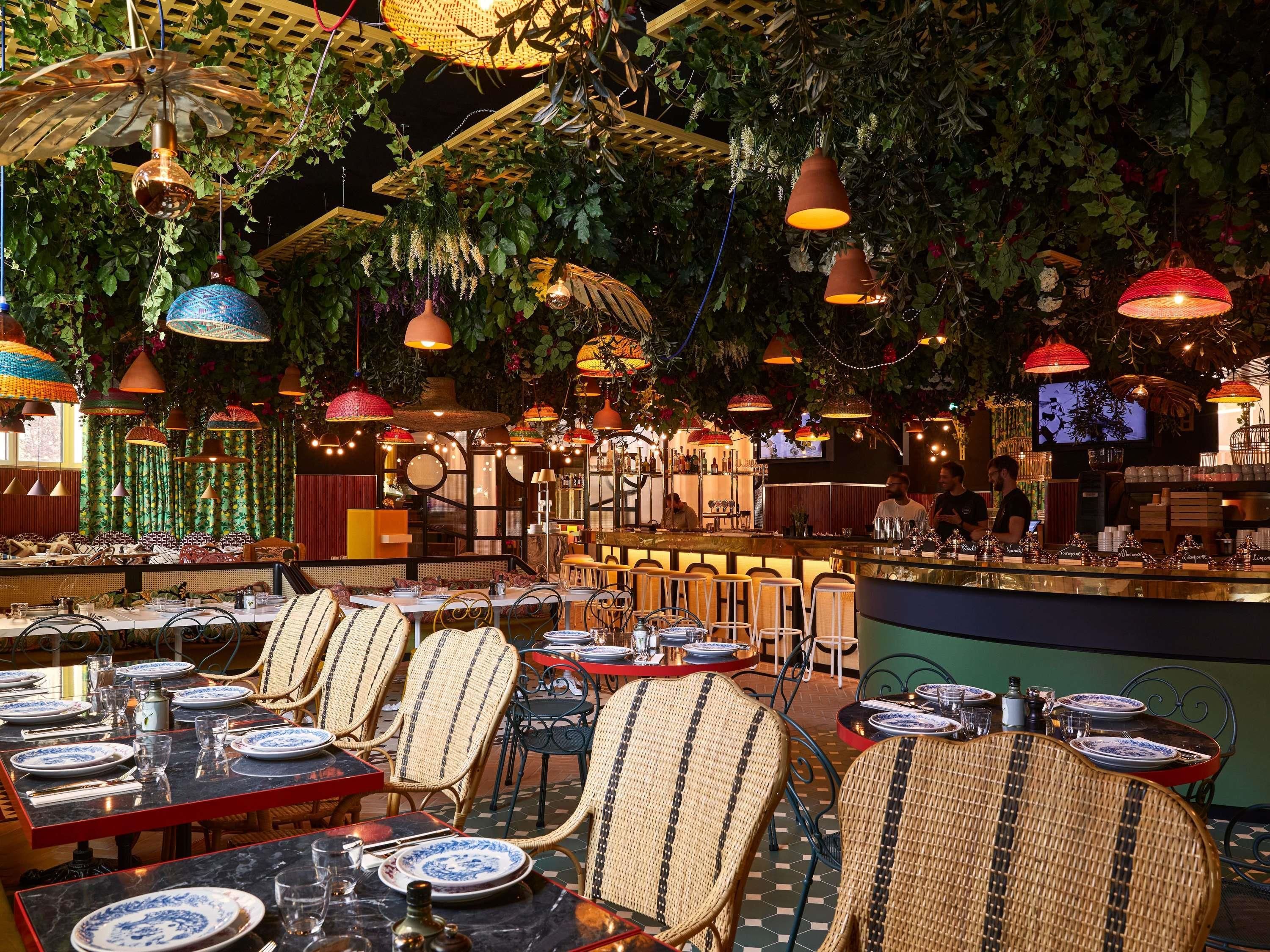 A restaurant with tables set for dining, a bar area, and hanging decorative lights.