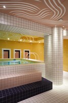 A swimming pool with tiled walls and a curved column.
