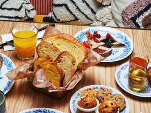 A breakfast setting with bread, muffins, and a glass of orange juice. - Mama Shelter Roma  (Rome)