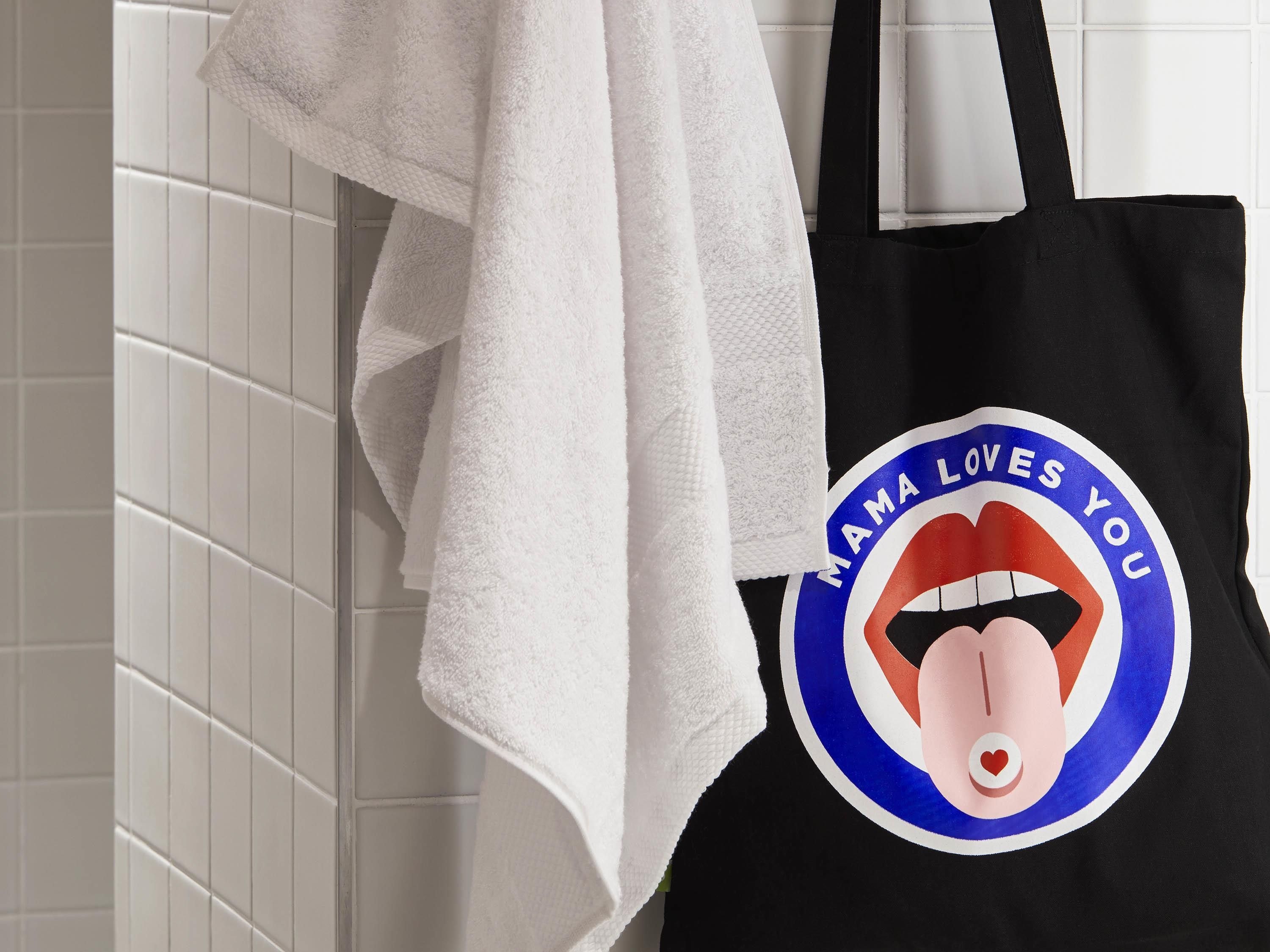 Una bolsa de tela negra con un gráfico de un rostro femenino y el texto 'MAMA LOVES YOU'.