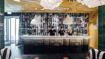 A bar area with a counter, bar stools, and a wall decorated with magazine-style images.
