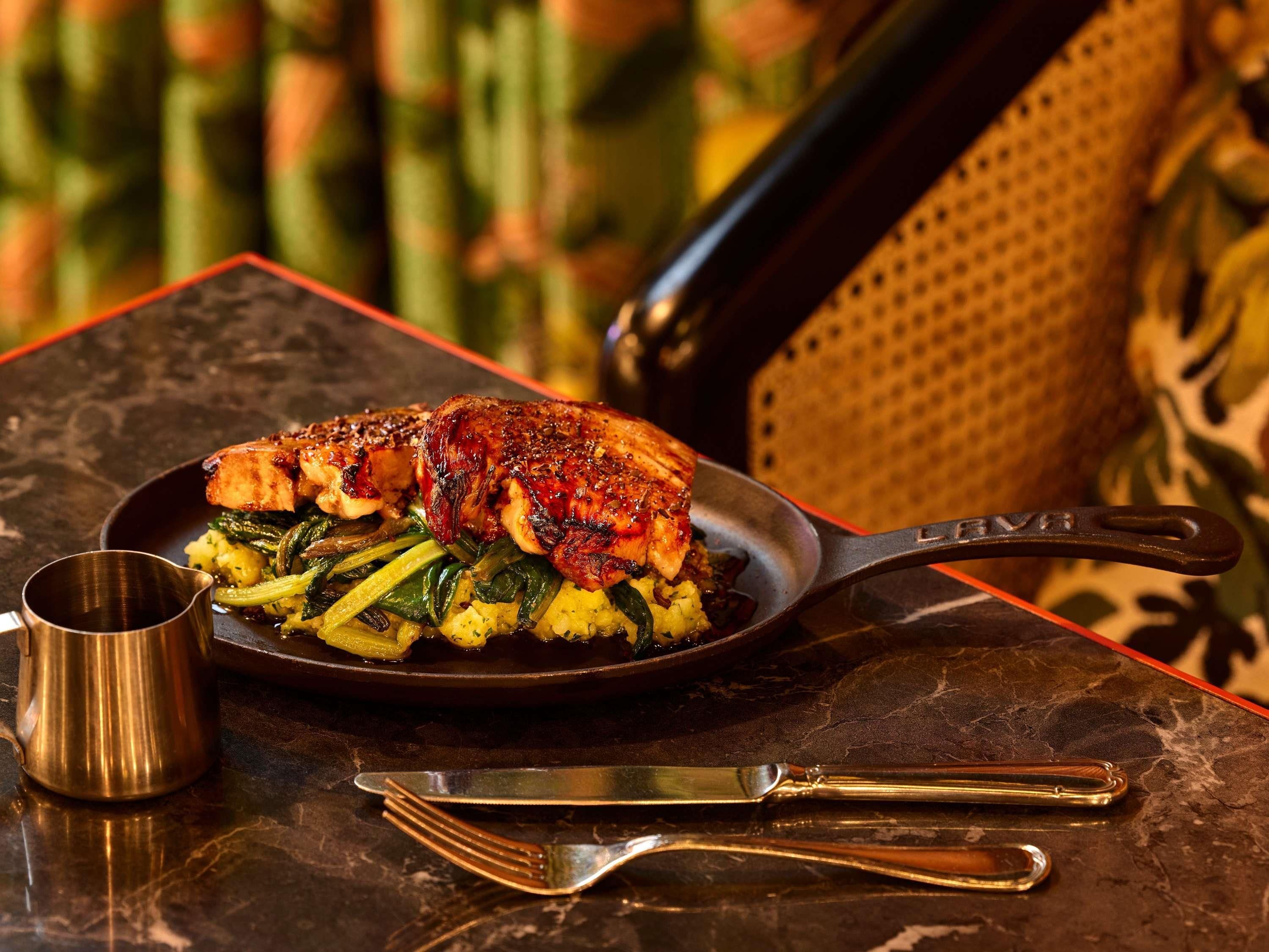 A meal with a pan, a fork, and a knife on a table.
