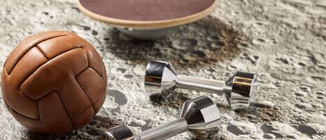 A brown leather ball and two metallic dumbbells on a textured surface.